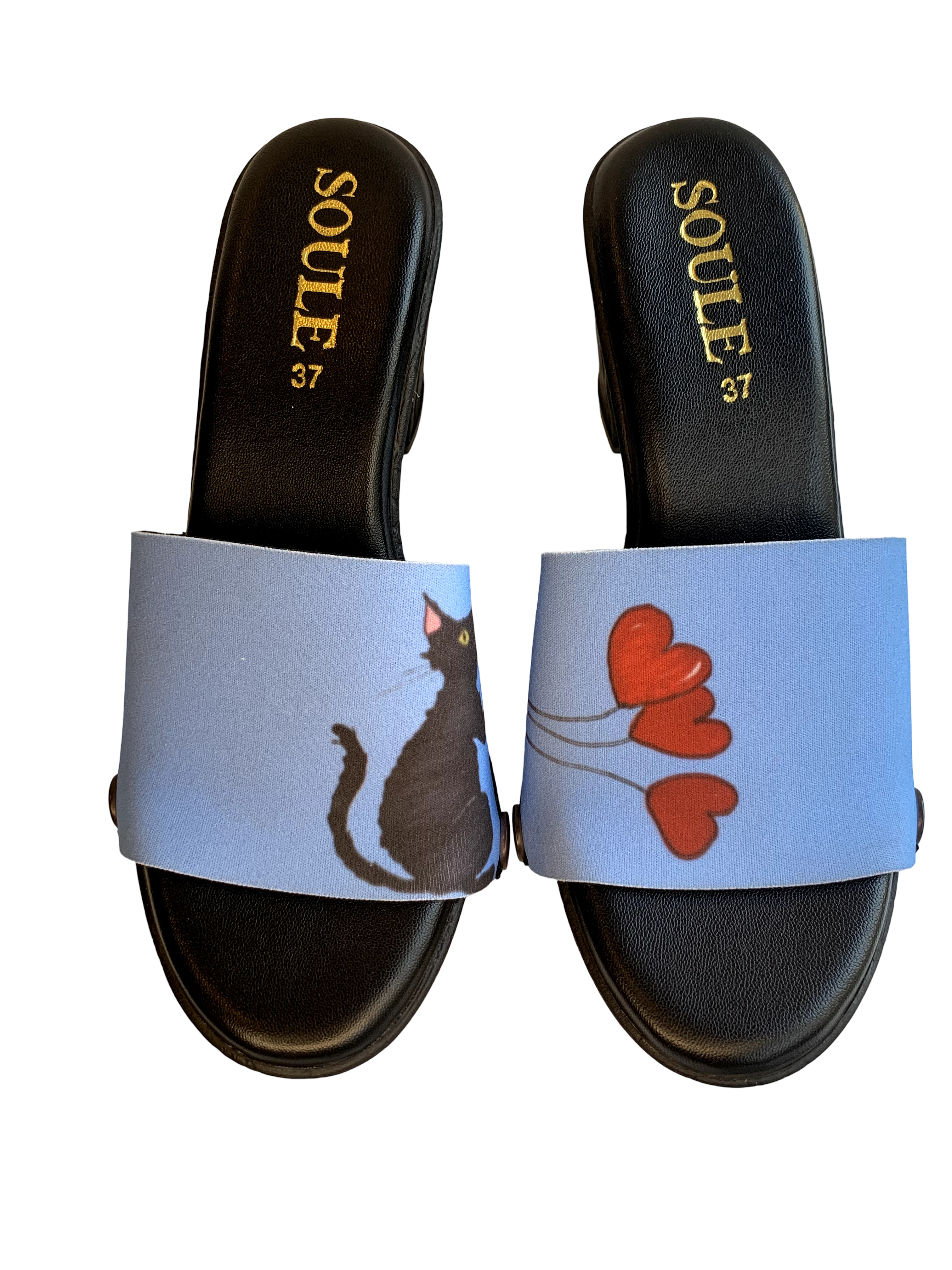 Party Cat snap-on shoe strap set close-up on black heel - illustrated dark cat in pink party hat and red heart balloons on sky blue by Soule