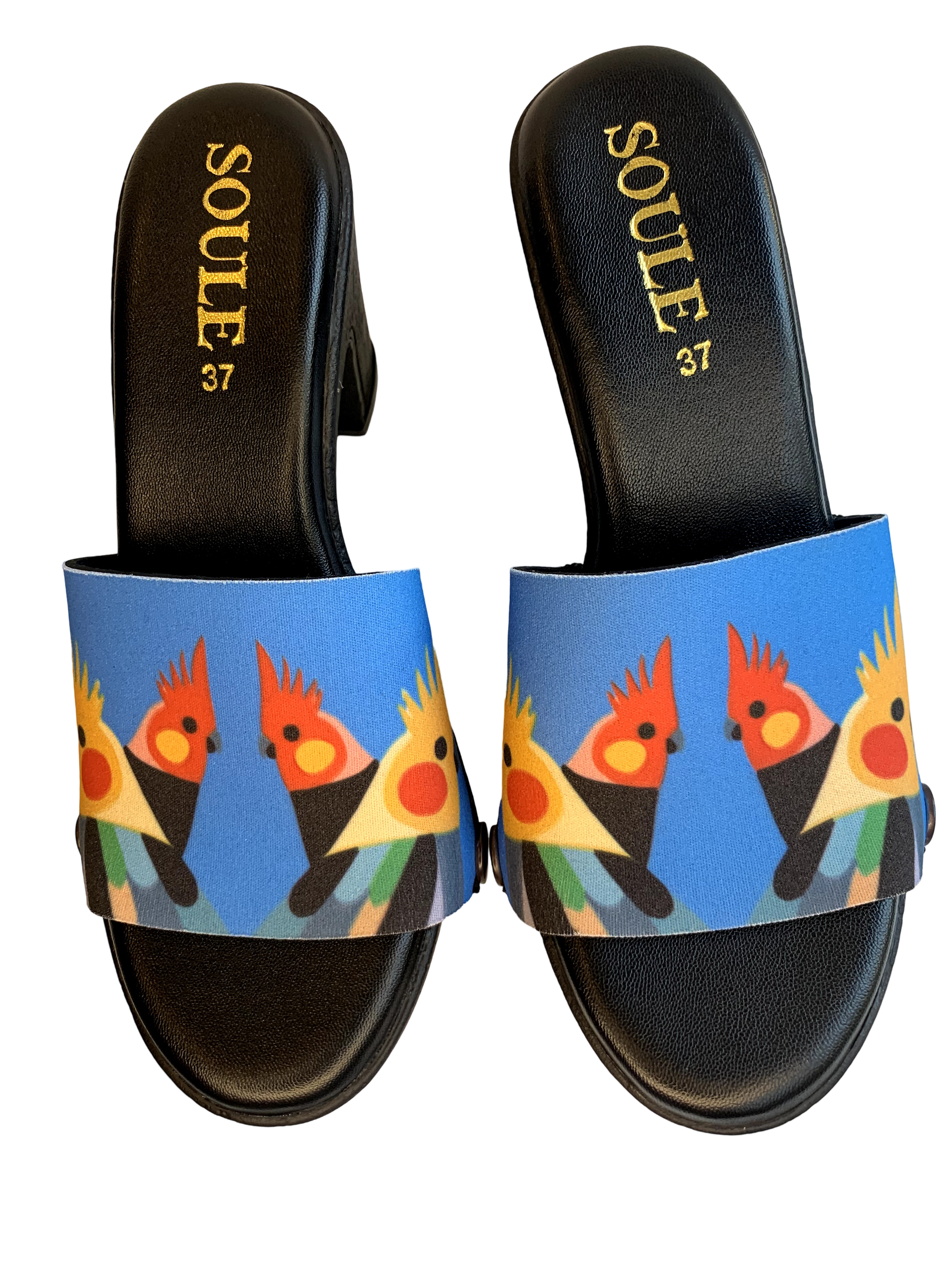 Cockatiel Choir snap-on shoe strap set close-up on black heel - bold row of illustrated cockatiels with yellow crests on vivid sky blue by Soule