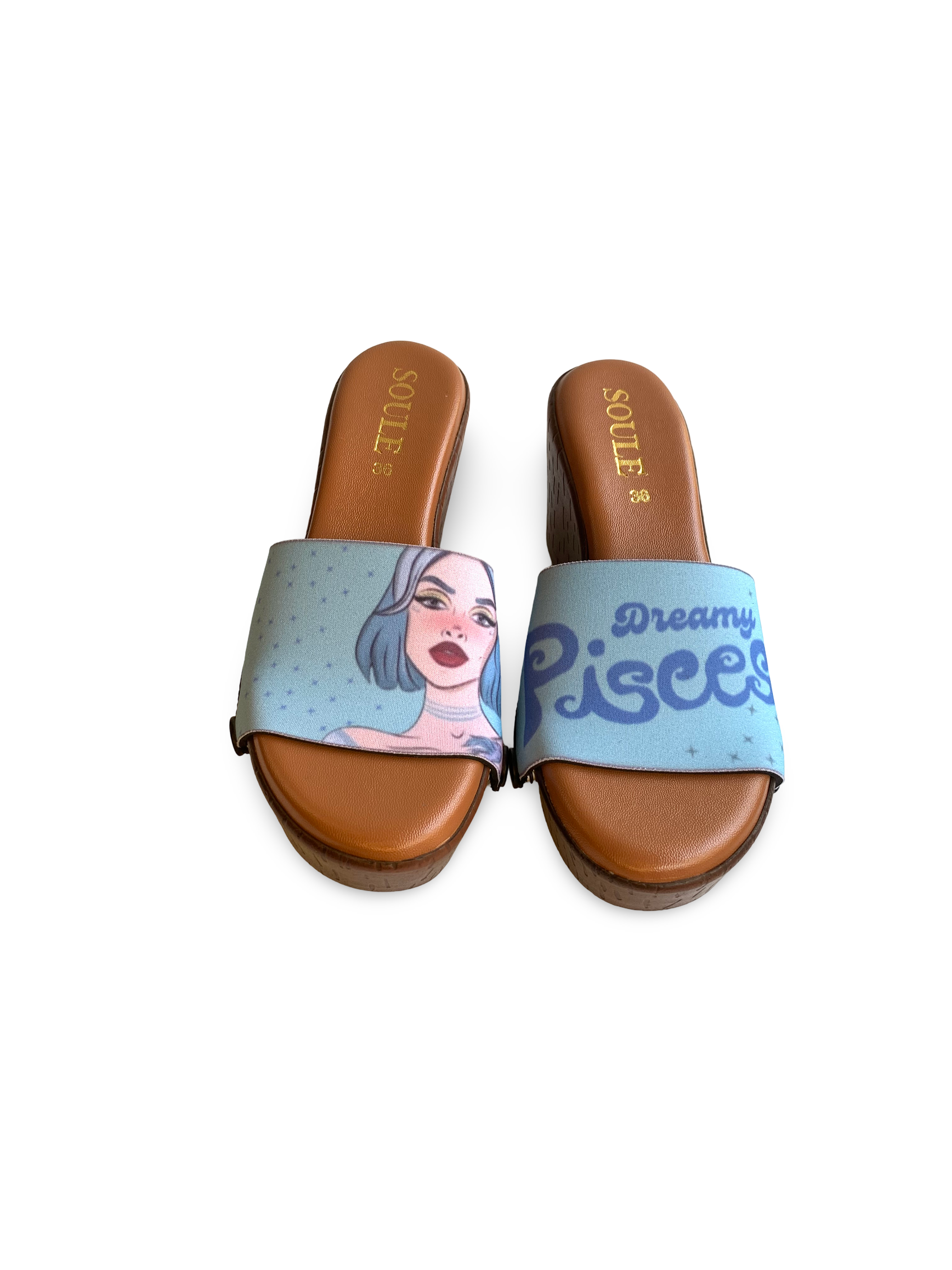 A pair of flat sandals with a blue interchangeable soft teal Dreamy Pisces zodiac strap strap featuring a celestial design and the text 'Dreamy Pisces'. The sandals have a brown base and black accents by soule footwear